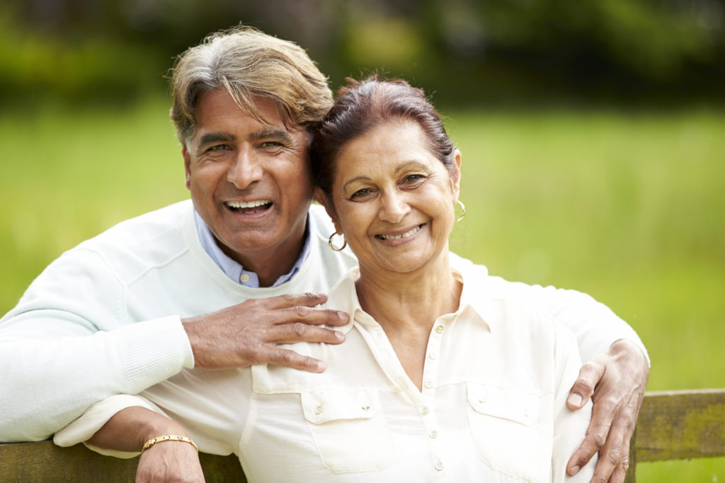 Senior Indian Couple smiling perfect smiles from the dental implants the received at Cigno Family Dental in Greenfield, WI.